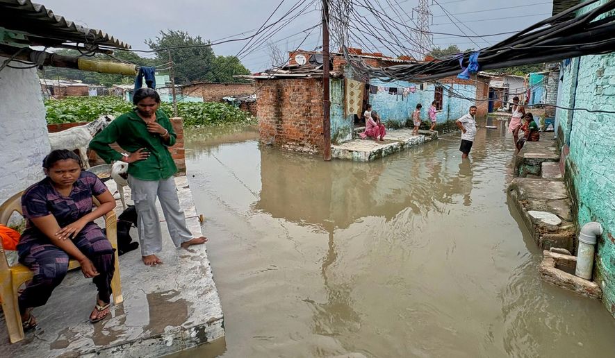 Residents of a low-lying neighborhood watch as floodwaters submerge their area following heavy rains in Kanpur, India, on Sept. 22, 2026. (AP Photo)