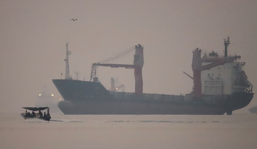 A motorboat passes an anchored cargo ship in the Strait of Hormuz off Bandar Abbas, Iran, early Monday, Sept. 28, 2026. (Amirhosein Khorgooi/ISNA via AP)