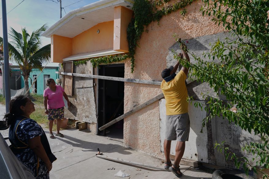 A man boards up a house's windows as Hurricane Polo approaches in Puerto San Carlos, Baja California Sur state, Mexico, Sunday, Sept. 27, 2026. (AP Photo/Eduardo Verdugo)