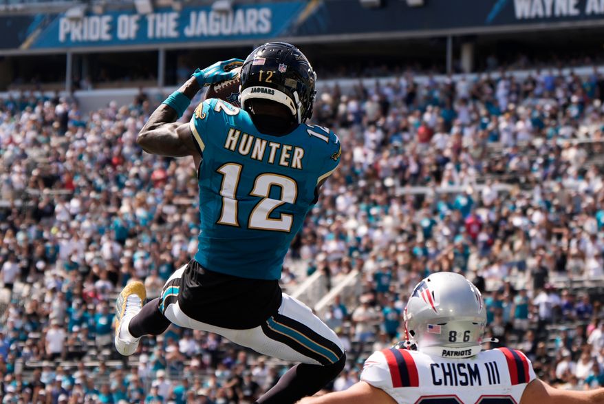 Jacksonville Jaguars wide receiver Travis Hunter (12) intercepts a pass against New England Patriots wide receiver Efton Chism III (86) in the first half during an NFL football game in Jacksonville, Fla., Sunday, Sept. 27, 2026. (AP Photo/Mike Stewart)