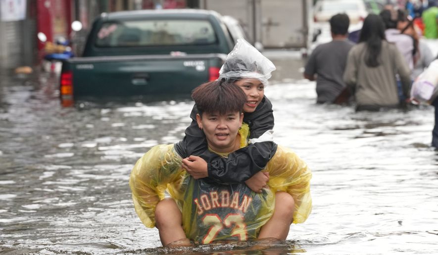 People wade through a flooded street after a heavy rain in Bangkok, Thailand, Monday, Sept. 28, 2026. (AP Photo/Sakchai Lalit)