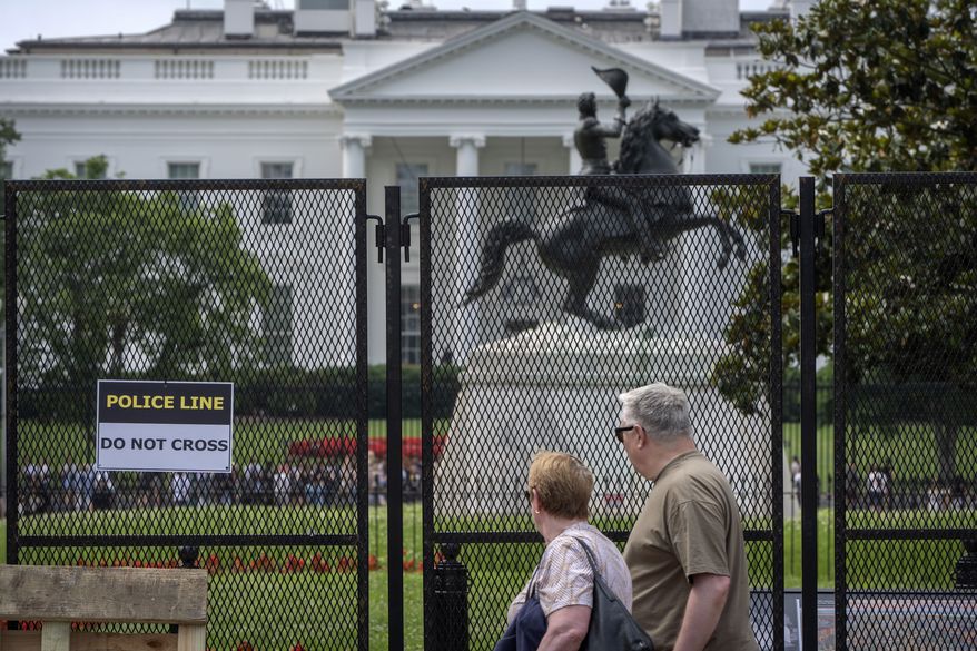 People walk past fencing around Lafayette Square near the White House in Washington on Monday, June 9, 2025. (AP Photo/Mark Schiefelbein) **FILE**
