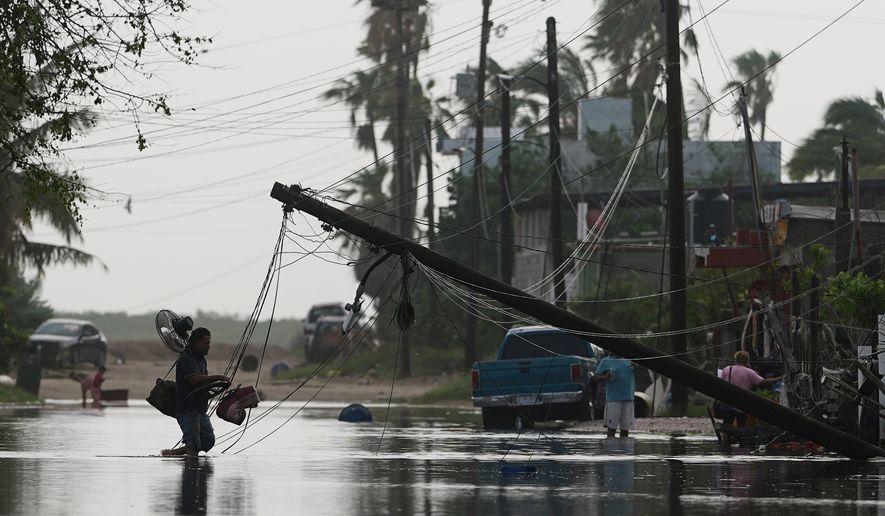 A man carries items through floodwater past downed electric lines after the passing of Hurricane Polo in Puerto San Carlos, Baja California Sur state, Mexico, Tuesday, Sept. 29, 2026. (AP Photo/Eduardo Verdugo)