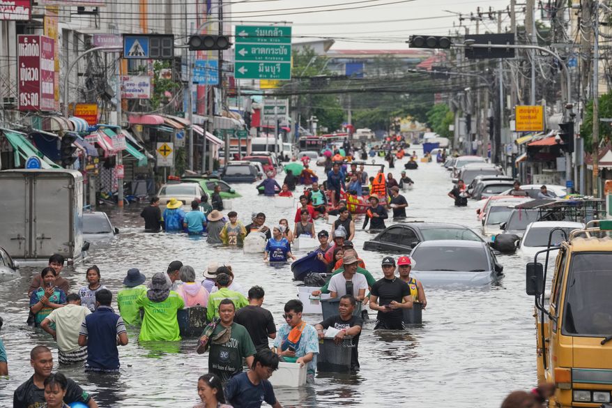 People wade through a flooded street after heavy rain in Bangkok, Thailand, Monday, Sept. 28, 2026. (AP Photo/Sakchai Lalit)