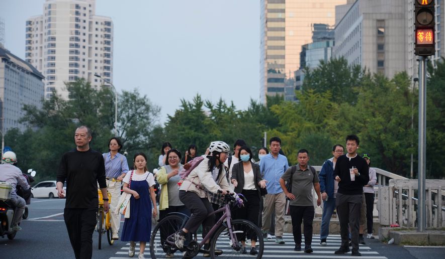 People cross an intersection in Beijing, Monday, Sept. 28, 2026. (AP Photo/Achmad Ibrahim)