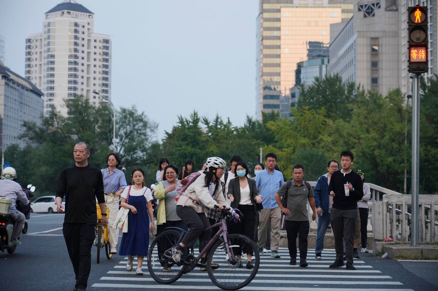 People cross an intersection in Beijing, Monday, Sept. 28, 2026. (AP Photo/Achmad Ibrahim)