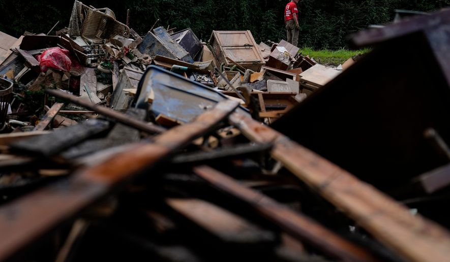FILE - A man stands near a pile of debris as residents clean up in Fleming-Neon, Ky., Aug. 5, 2022, after massive flooding the previous week. (AP Photo/Brynn Anderson, File)