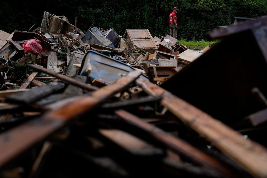 FILE - A man stands near a pile of debris as residents clean up in Fleming-Neon, Ky., Aug. 5, 2022, after massive flooding the previous week. (AP Photo/Brynn Anderson, File)