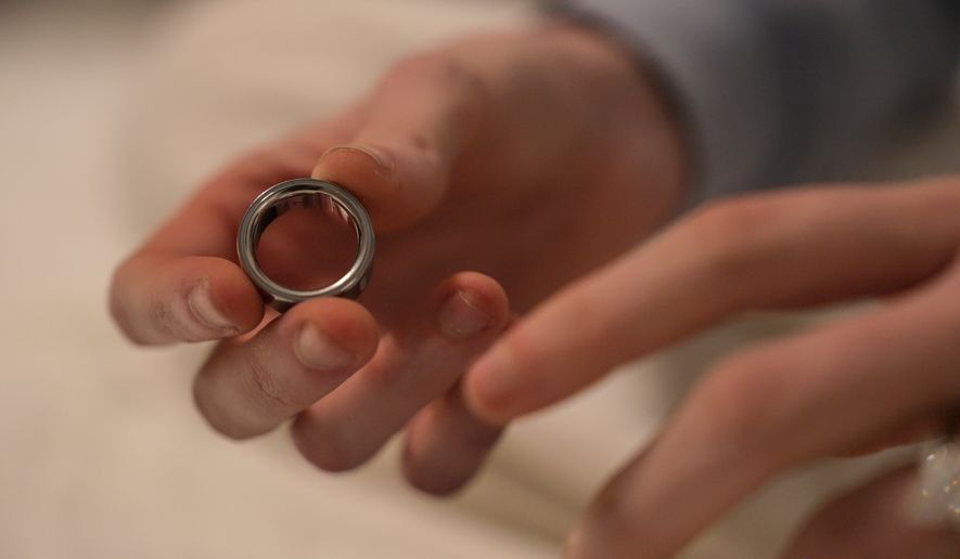 FILE - Middle school teacher Kate Stoye puts on an Oura ring, a wearable sleep tracking device, Wednesday, Jan. 7, 2026, in Hiram, Ga. (AP Photo/Emilie Megnien, file)