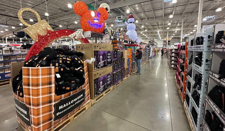 A shopper holds a child as they look at items on sale for Halloween in a Costco warehouse Sunday, Sept. 13, 2026, in Sheridan, Colo. (AP Photo/David Zalubowski)