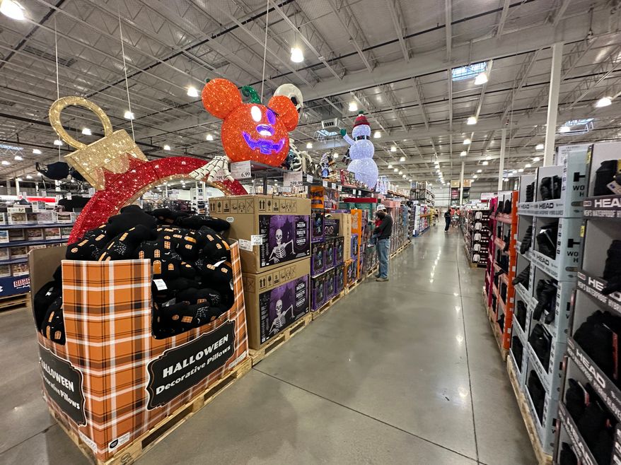 A shopper holds a child as they look at items on sale for Halloween in a Costco warehouse Sunday, Sept. 13, 2026, in Sheridan, Colo. (AP Photo/David Zalubowski)