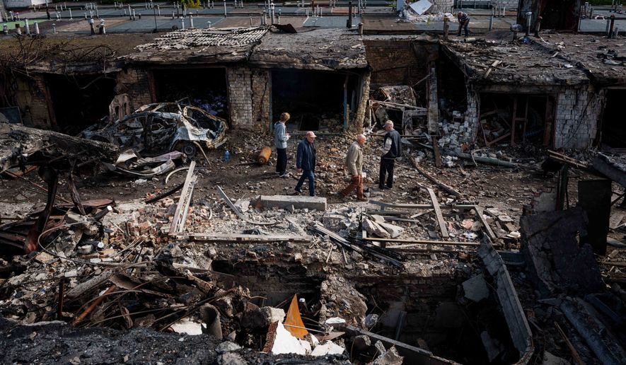 People walk in front of garages destroyed in a Russian missile strike on Vyshhorod, Kyiv region, Ukraine, Wednesday, Sept. 30, 2026. (AP Photo/Evgeniy Maloletka)