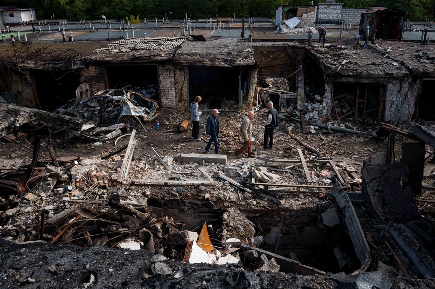 People walk in front of garages destroyed in a Russian missile strike on Vyshhorod, Kyiv region, Ukraine, Wednesday, Sept. 30, 2026. (AP Photo/Evgeniy Maloletka)