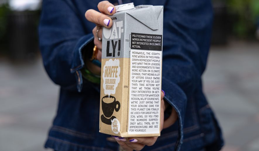 Caroline Reid, with the Swedish oat milk company Oatly, shows a sample of the company's new milk carton climate campaign for New York Climate Week on Wednesday, Sept. 23, 2026, in New York. (AP Photo/Anton L. Delgado)