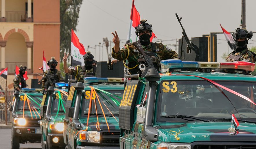 Iraqi security officers flash victory signs as they ride on vehicles decorated with national flags and ribbons during a convoy celebrating the complete withdrawal of U.S. troops from Iraq, in Baghdad, Iraq, Wednesday, Sept. 30, 2026. (AP Photo/Hadi Mizban)