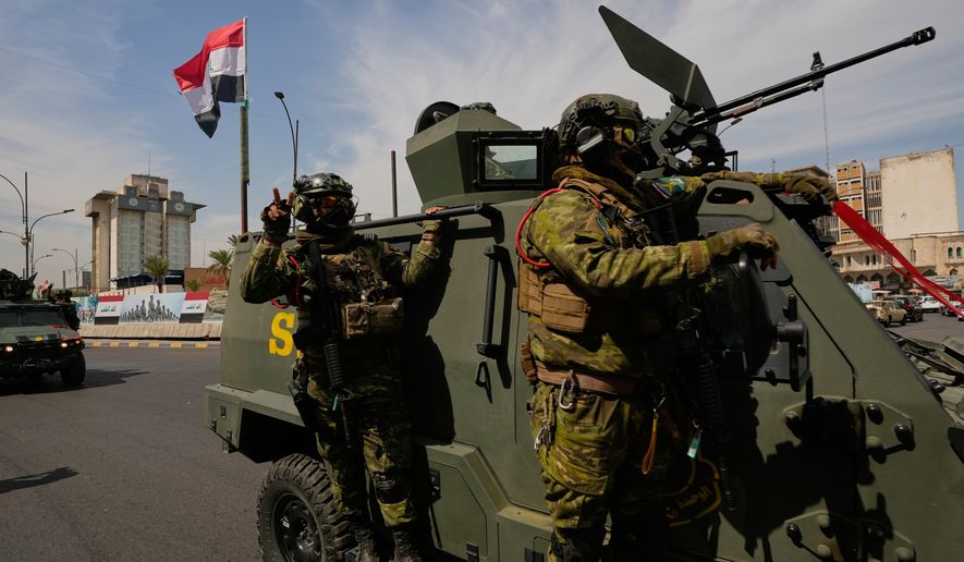 Iraqi police officers stand beside security vehicles decorated with national flags and ribbons during a convoy celebrating the complete withdrawal of U.S. troops from Iraq, in Baghdad, Iraq, Wednesday, Sept. 30, 2026. (AP Photo/Hadi Mizban)