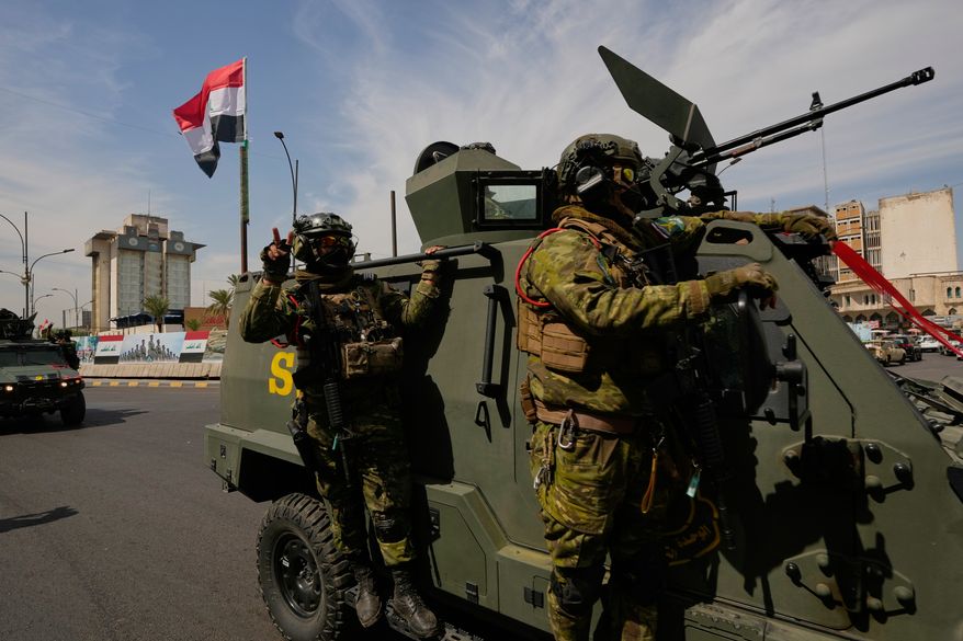 Iraqi police officers stand beside security vehicles decorated with national flags and ribbons during a convoy celebrating the complete withdrawal of U.S. troops from Iraq, in Baghdad, Iraq, Wednesday, Sept. 30, 2026. (AP Photo/Hadi Mizban)