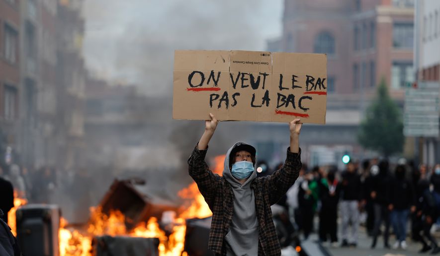 A students holds a board reading, "we want the BAC (High School Diploma) Not the BAC (Anti-criminality units)" during a protest to demand more resources at school, in Lille, France, Thursday, Oct. 1, 2026. (AP Photo/Jean-Francois Badias)