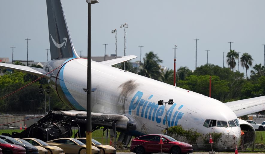An Amazon cargo plane lies damaged near a parking lot two days after overshooting a runway at Miami International Airport, Tuesday, Sept. 8, 2026, in Miami. (AP Photo/Rebecca Blackwell)