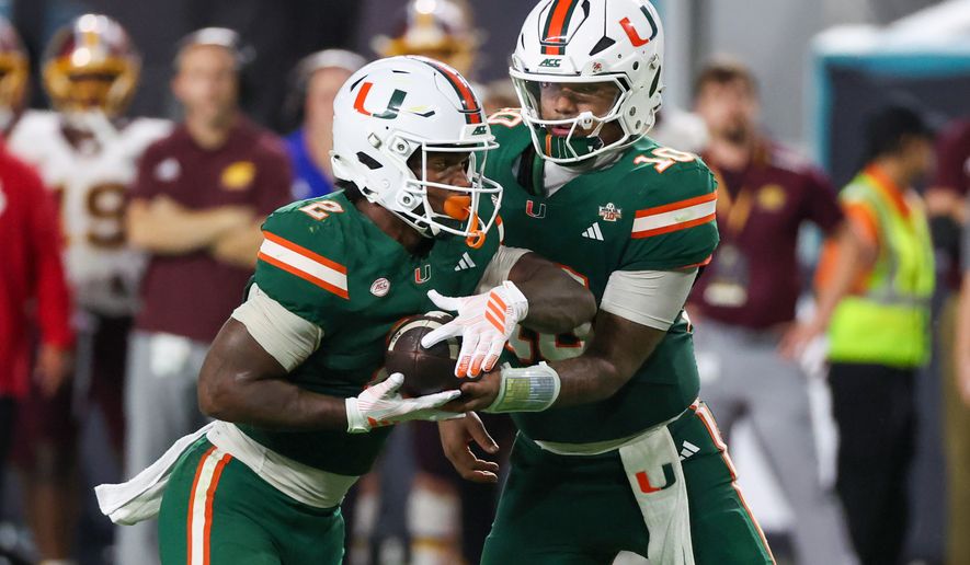 Miami quarterback Darian Mensah (10) hands off the ball to running back Jordan Lyle (2) against Central Michigan during the second half of an NCAA college football game, Saturday, Sept. 26, 2026, in Miami Gardens, Fla. (AP Photo/David Santiago)