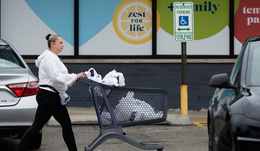 A woman pushes a shopping cart as she leaves a grocery store in Arlington Heights, Ill., Wednesday, Sept. 30, 2026. (AP Photo/Nam Y. Huh)