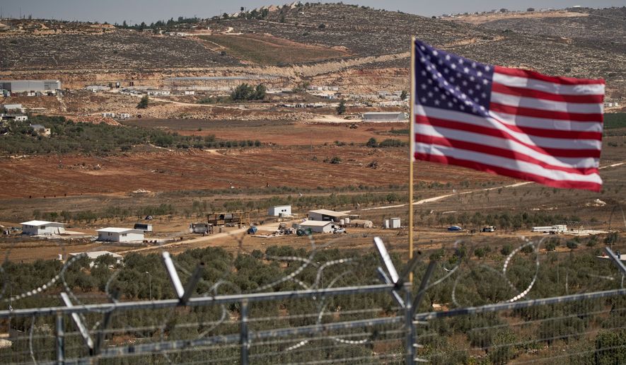 FILE - A U.S. flag waves at the entrance of a Palestinian house as an Israeli settler outpost stands in the middle of a valley next to olive trees in the West Bank town of Turmus Ayya, Sept. 9, 2026. (AP Photo/Leo Correa, File)