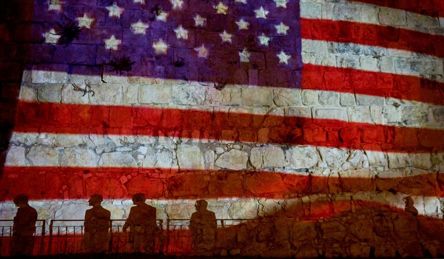 FILE - Pedestrians are silhouetted against a projection of the American flag on the walls of Jerusalem's Old City, July 5, 2026, displayed in honor of the 250th anniversary of U.S. independence. (AP Photo/Ohad Zwigenberg, File)