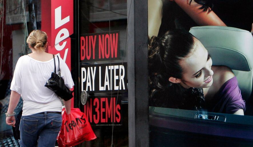 A woman walks by a sign "Buy now pay later" at a store in Bangalore, India, on Sept. 10, 2009. (AP Photo/Aijaz Rahi, File)