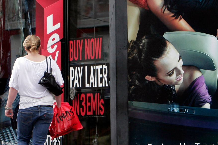 A woman walks by a sign "Buy now pay later" at a store in Bangalore, India, on Sept. 10, 2009. (AP Photo/Aijaz Rahi, File)