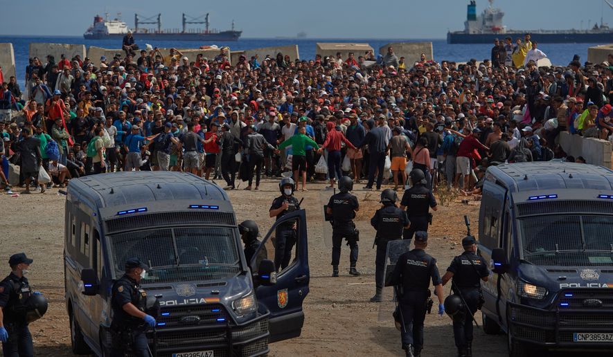 FILE - Migrants who crossed from Morocco into Spain return to a beach after being expelled from the area the previous day, as Spanish police escort them in the Spanish exclave of Ceuta, Aug. 21, 2026. (AP Photo/Antonio Sempere, File)