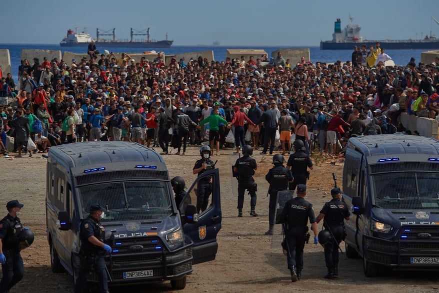 FILE - Migrants who crossed from Morocco into Spain return to a beach after being expelled from the area the previous day, as Spanish police escort them in the Spanish exclave of Ceuta, Aug. 21, 2026. (AP Photo/Antonio Sempere, File)