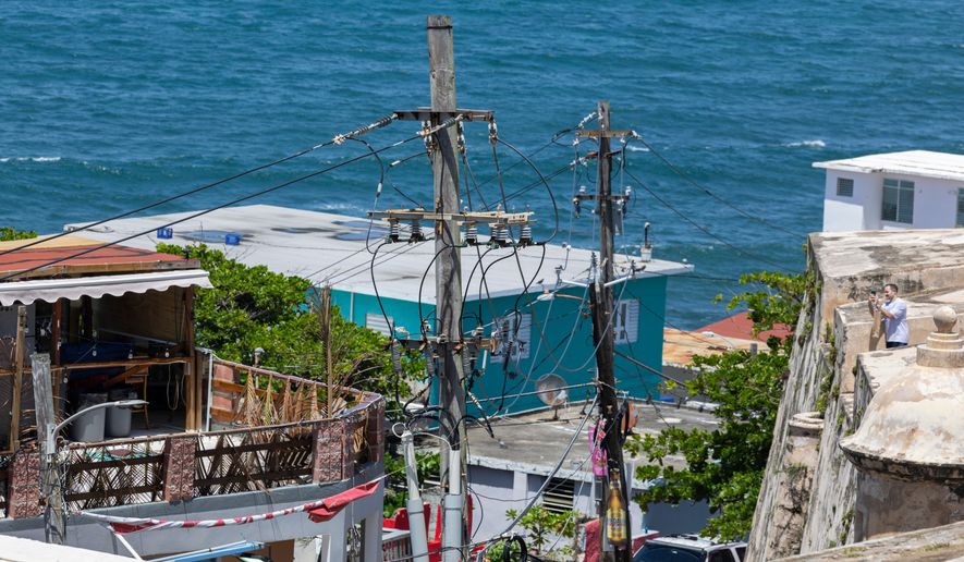 FILE - Power lines and utility poles stand in front of La Perla neighborhood along the coast in Old San Juan, Puerto Rico, Aug. 15, 2025. (AP Photo/Alejandro Granadillo, File)
