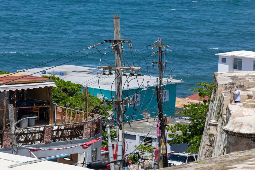 FILE - Power lines and utility poles stand in front of La Perla neighborhood along the coast in Old San Juan, Puerto Rico, Aug. 15, 2025. (AP Photo/Alejandro Granadillo, File)