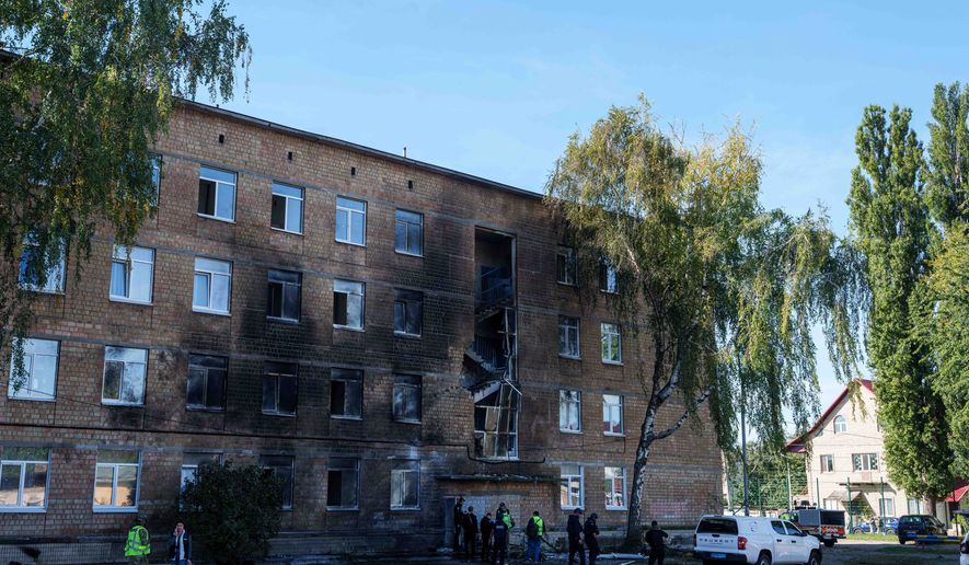 Police officers look at a school damaged by a Russian drone strike in Kyiv, Ukraine, Thursday, Oct. 1, 2026. (AP Photo/Evgeniy Maloletka)