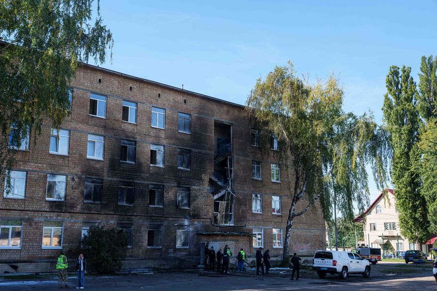 Police officers look at a school damaged by a Russian drone strike in Kyiv, Ukraine, Thursday, Oct. 1, 2026. (AP Photo/Evgeniy Maloletka)
