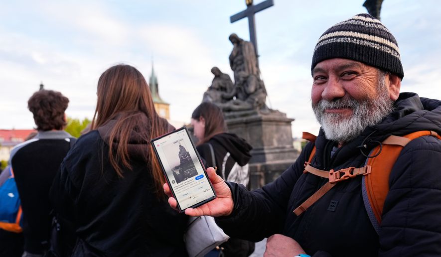 Jorge Sanchez from Los Angeles displays a famous photo of two members of Depeche Mode, taken by Dutch photographer Anton Corbijn in 1988, as he waits in line to recreate this image by the Pieta statue at the Charles Bridge in Prague, Czech Republic, Thursday, Sept. 24, 2026. (AP Photo/Petr David Josek)