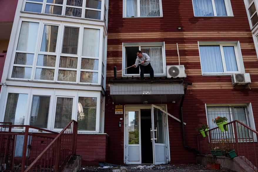 A man clears the rubble from a canopy over the entrance of a multi-storey residential building damaged following a Russian drone strike, in Kyiv, Ukraine, Friday, Oct. 2, 2026. (AP Photo/Evgeniy Maloletka)