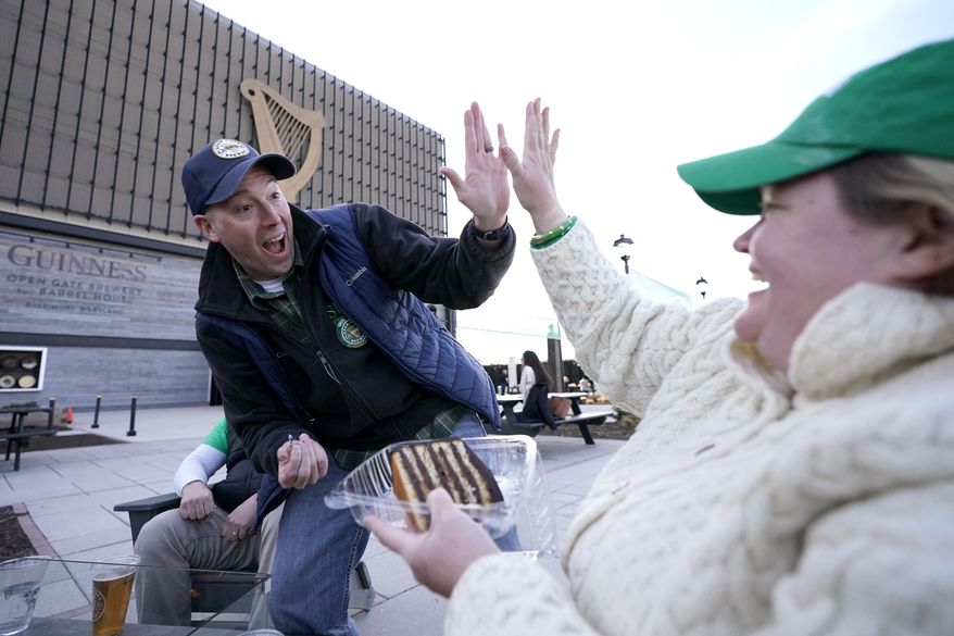 Nick Snyder, right, of Washington, gives a high five to Megan Daly, of Annapolis, Md., after she blew out a candle he was holding while celebrating her birthday at the Guinness Open Gate Brewery, Saturday, March 13, 2021, in Halethorpe, Md. AP Photo/Julio Cortez)