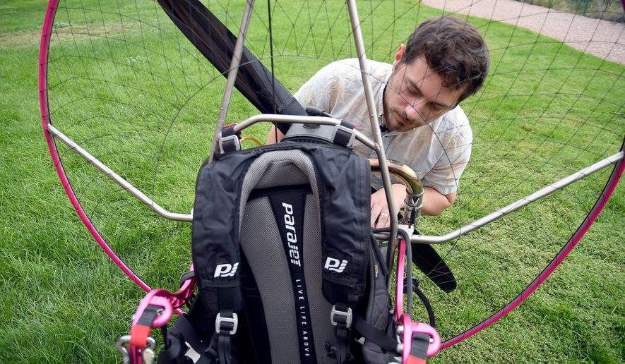 Jake Hutzler, who often flies to his air traffic controller job, inspects his paramotor outside his home in Pueblo, Colo., on Thursday, Oct. 1, 2026. (AP Photo/Thomas Peipert)