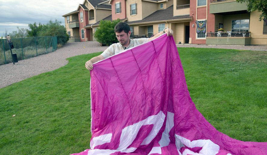 Jake Hutzler, who often flies to his air traffic controller job, shakes sand from his paramotor wing outside his home in Pueblo, Colo., on Thursday, Oct. 1, 2026. (AP Photo/Thomas Peipert)