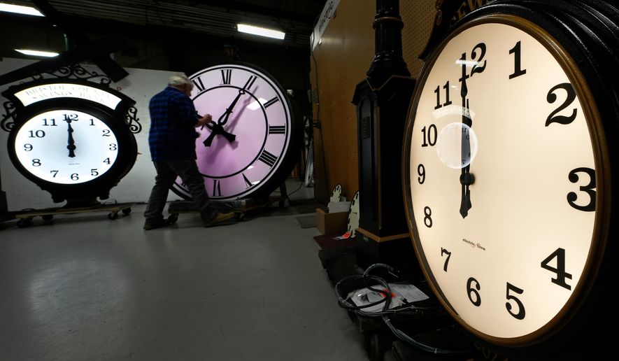 Clockmaker Scott Gow adjusts the hands of a clock at the Electric Time Company, Oct. 30, 2024, in Medfield, Mass. (AP Photo/Charles Krupa, File)