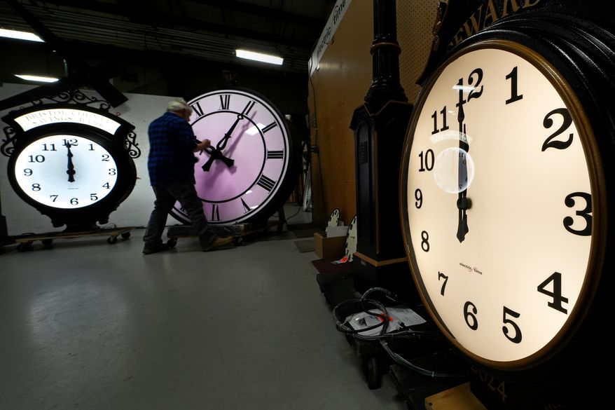 Clockmaker Scott Gow adjusts the hands of a clock at the Electric Time Company, Oct. 30, 2024, in Medfield, Mass. (AP Photo/Charles Krupa, File)