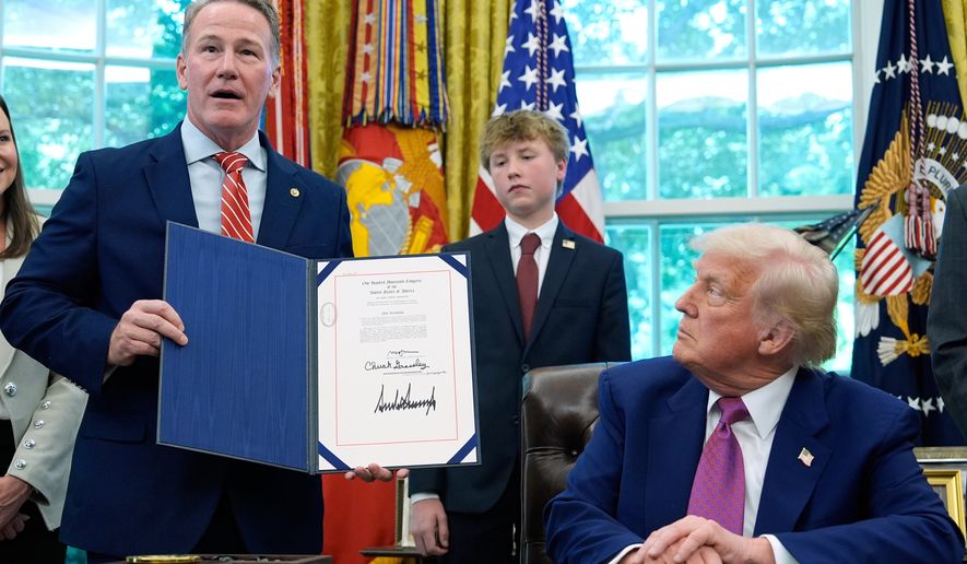 President Donald Trump listens as Sen. Jon Husted, R-Ohio, speaks while holding up a signed resolution in the Oval Office of the White House, May 9, 2025, in Washington. (AP Photo/Alex Brandon, File)