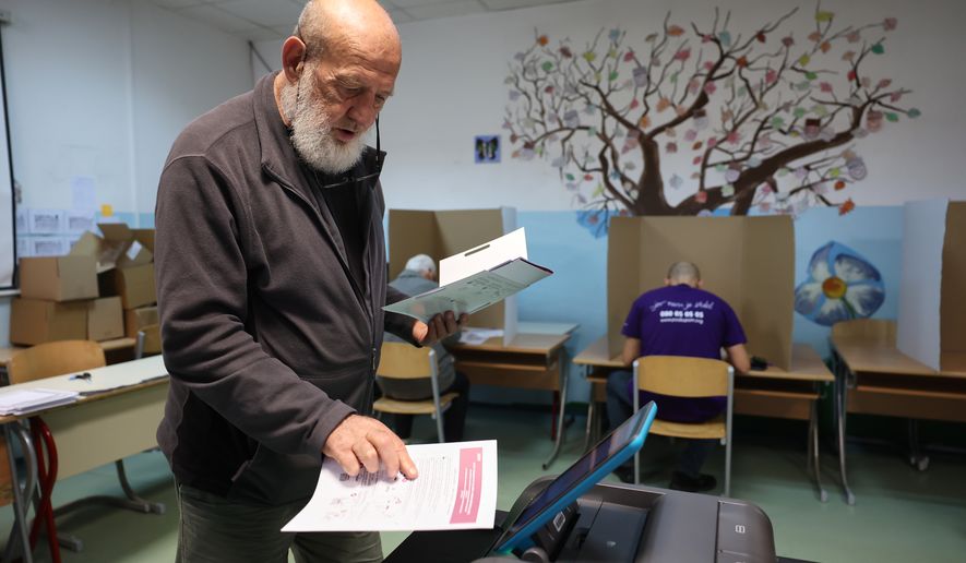 A man places his ballot into an electronic ballot box during the general election in Sarajevo, Bosnia, Sunday, Oct. 4, 2026. (AP Photo/Armin Durgut)