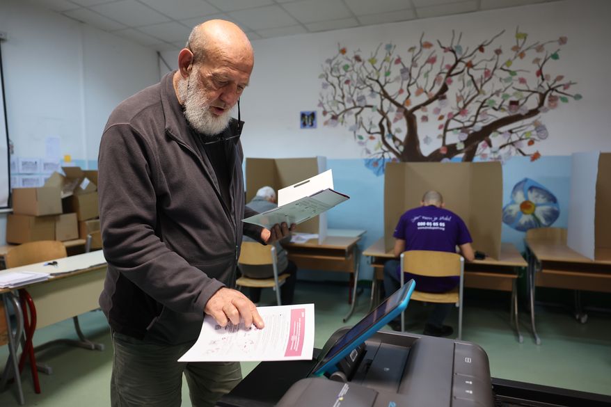 A man places his ballot into an electronic ballot box during the general election in Sarajevo, Bosnia, Sunday, Oct. 4, 2026. (AP Photo/Armin Durgut)