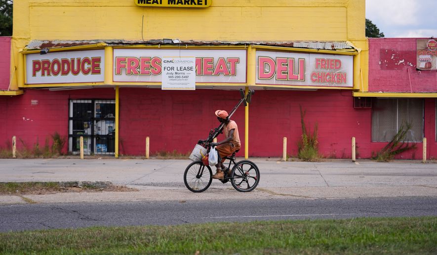 A man rides his bicycle past a closed meat market in the Scotlandville section of Baton Rouge, La., Wednesday, Sept. 16, 2026. (AP Photo/Gerald Herbert)