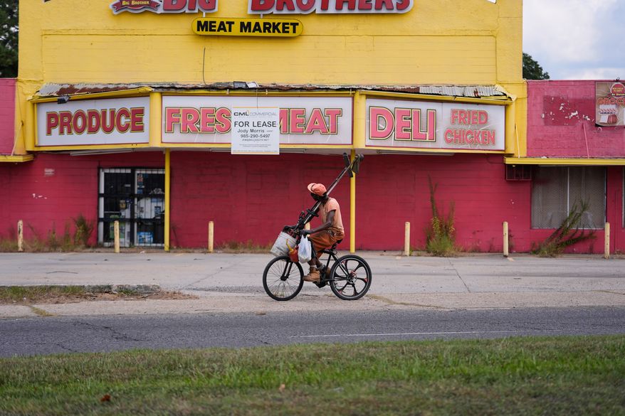 A man rides his bicycle past a closed meat market in the Scotlandville section of Baton Rouge, La., Wednesday, Sept. 16, 2026. (AP Photo/Gerald Herbert)