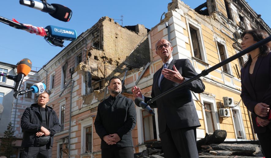 Ukraine's President Volodymyr Zelenskyy, centre, and German Chancellor Friedrich Merz speak to media with National Academy of science building damaged after a Russian drone strike, on the background, Kyiv, Ukraine, Sunday, Oct. 4, 2026. (AP Photo/Evgeniy Maloletka)
