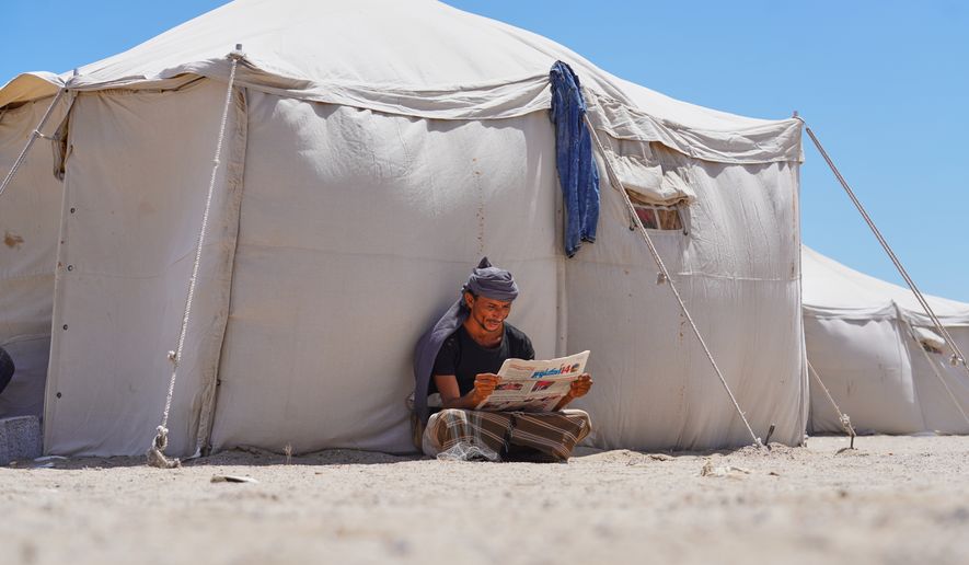 A displaced Yemeni reads a newspaper at the Al-Firdaws camp in Ras Imran on the western outskirts of Aden, Yemen, Monday, Oct. 5, 2026. (AP Photo/Abdulnasser Alseddik)