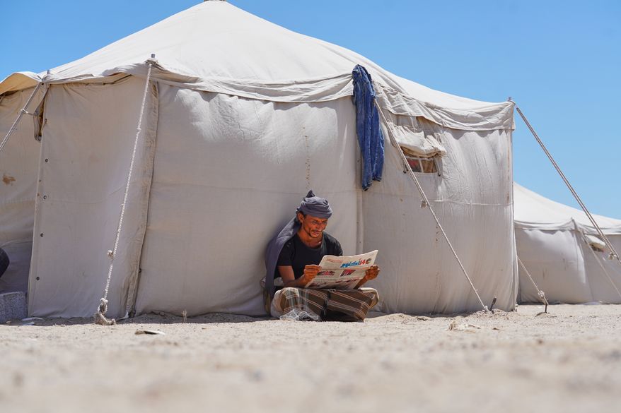 A displaced Yemeni reads a newspaper at the Al-Firdaws camp in Ras Imran on the western outskirts of Aden, Yemen, Monday, Oct. 5, 2026. (AP Photo/Abdulnasser Alseddik)